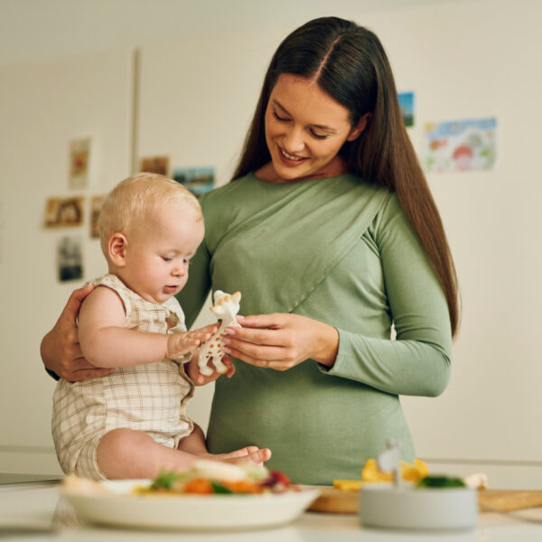 Bezbrižni trenuci majke i bebe u kuhinji – igra s popularnom žirafom.