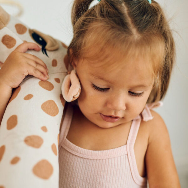 Djevojčica drži plišanu žirafu.