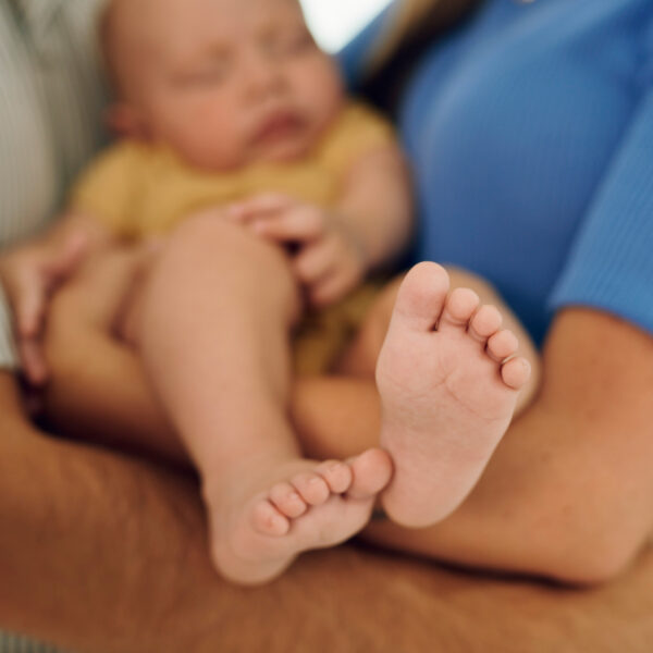 Novorođenče spava mirno u naručju roditelja – trenutak ljubavi i njege.