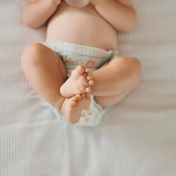Beba leži s podignutim nogama – znakovi zatvora kod dojenčadi.