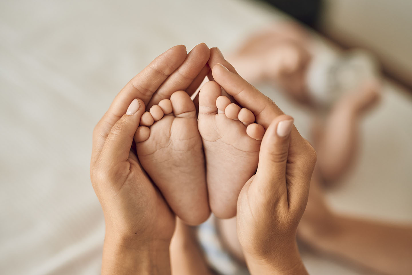 Bebine noge u majčinom naručju – nježnost i ljubav majke prema bebi.