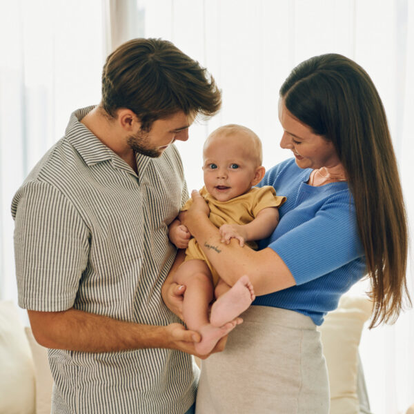 Roditelji drže svoju bebu u naručju – sretni trenuci obiteljske ljubavi.