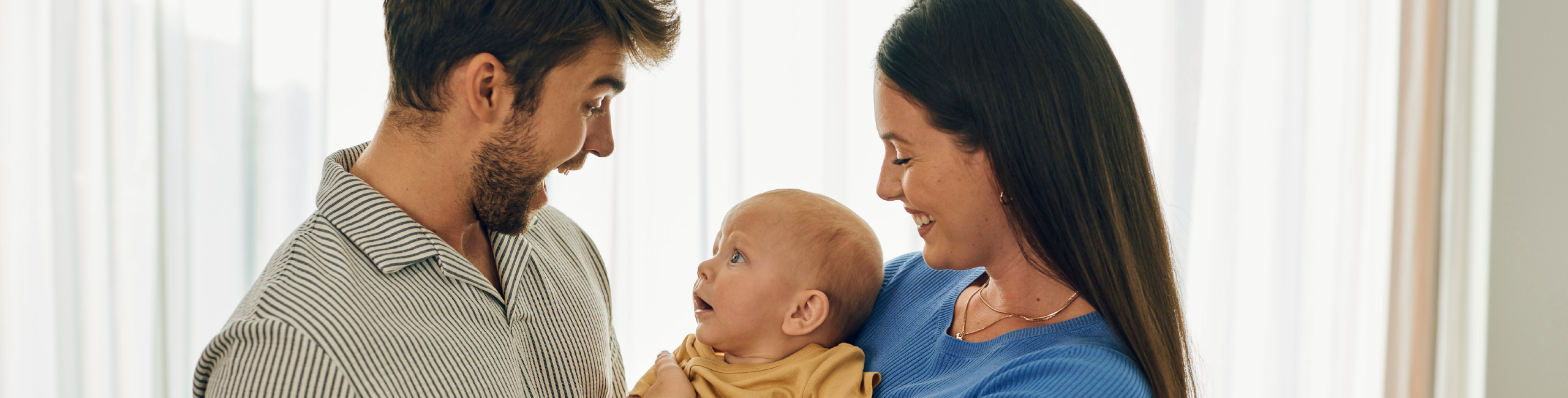 Roditelji drže svoju bebu u naručju – sretni trenuci obiteljske ljubavi.