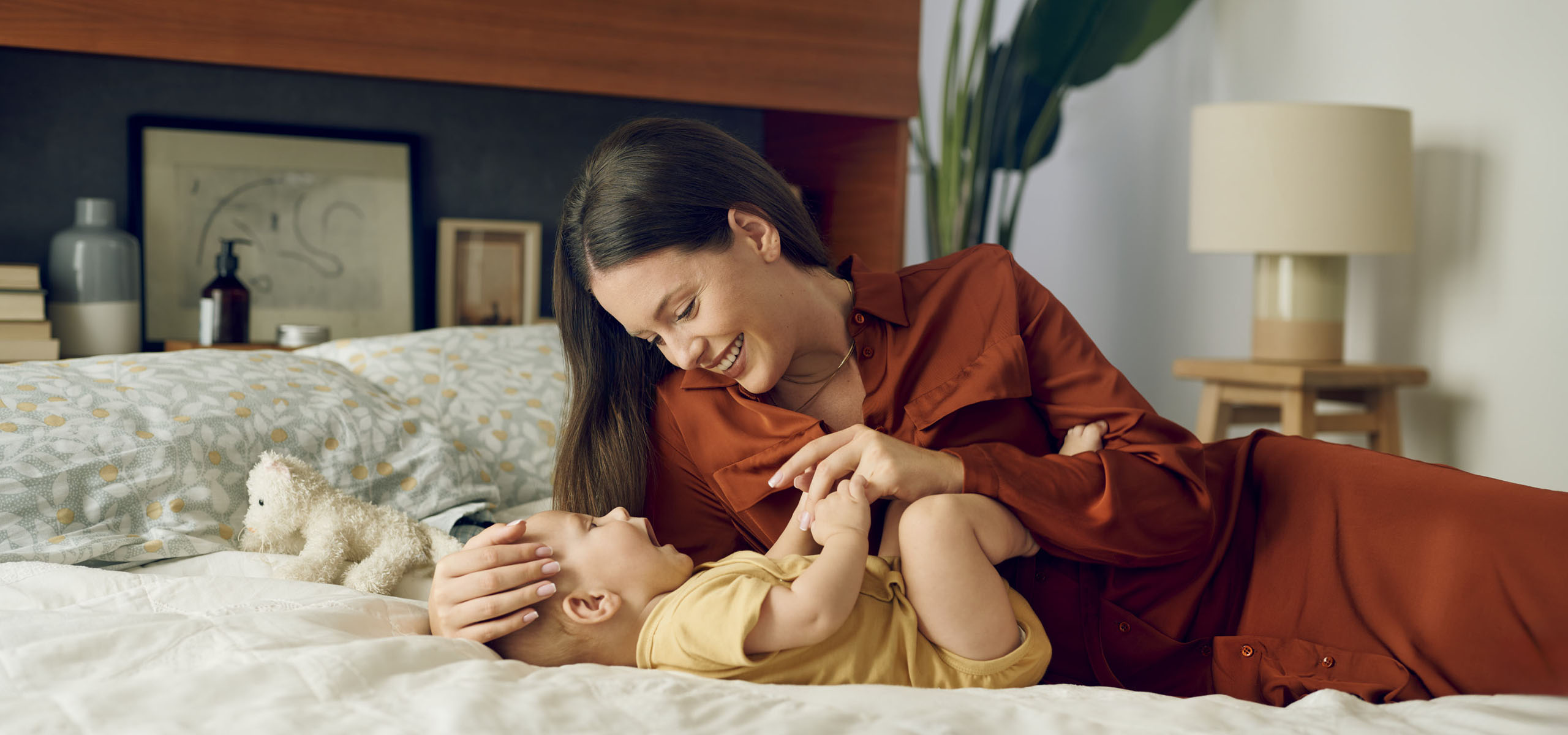Majka i beba uživaju u igri na krevetu – sretni trenuci zajedništva.