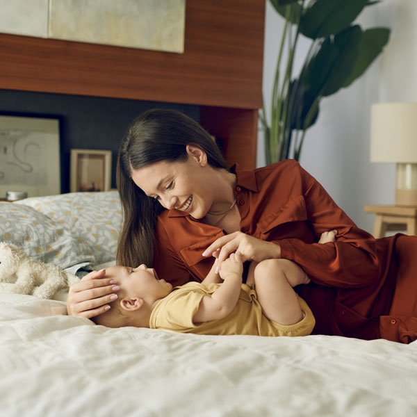 Mama se igra s novorođenčetom u krevetu