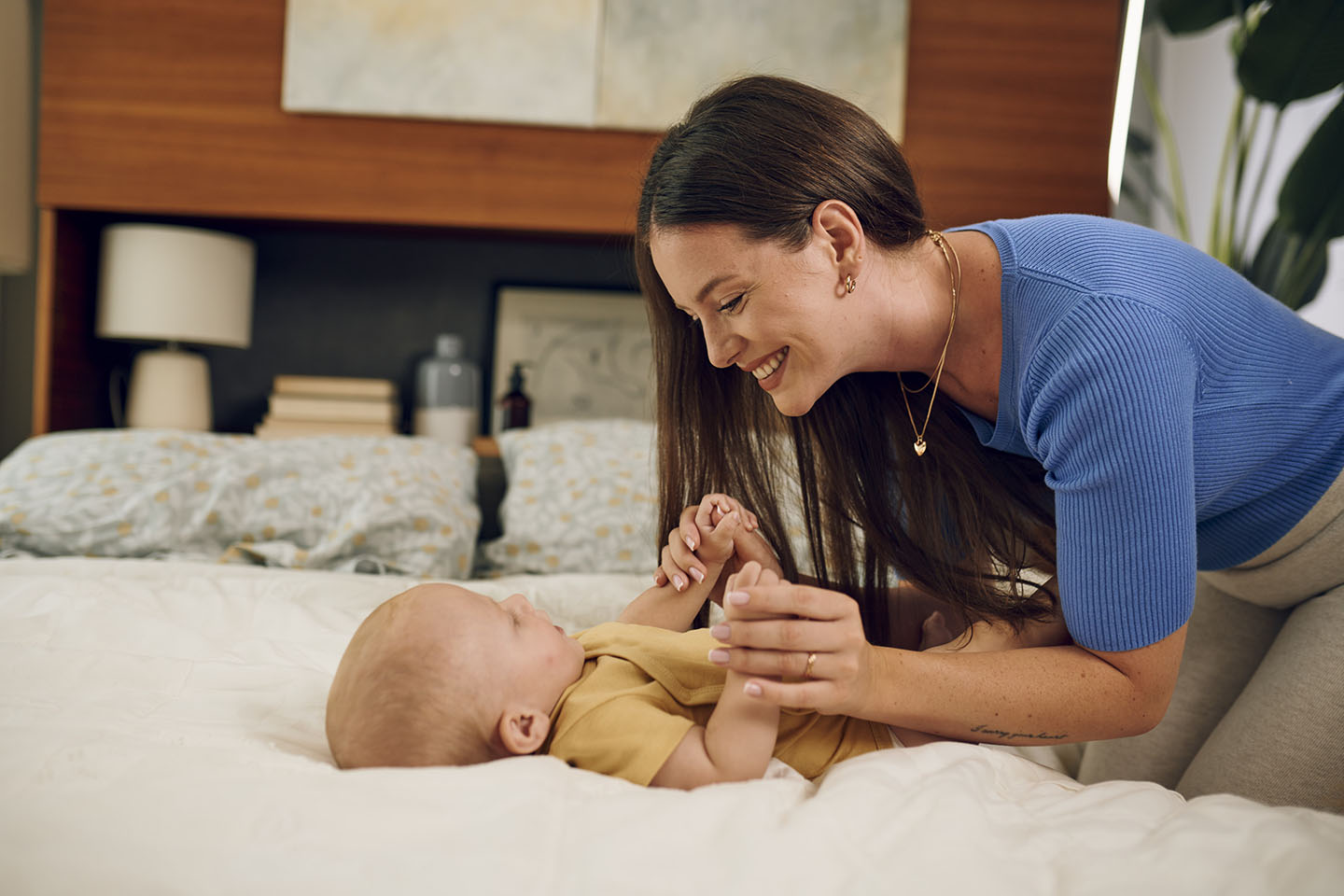 Majka i beba uživaju u igri na krevetu – sretni trenuci zajedništva.