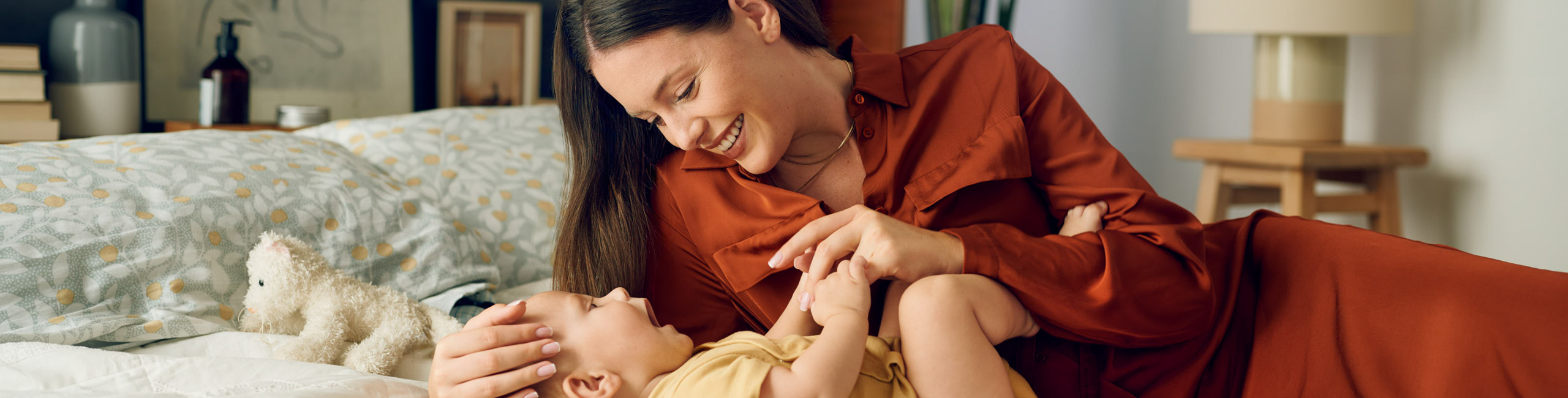 Majka i beba uživaju u igri na krevetu – sretni trenuci zajedništva.