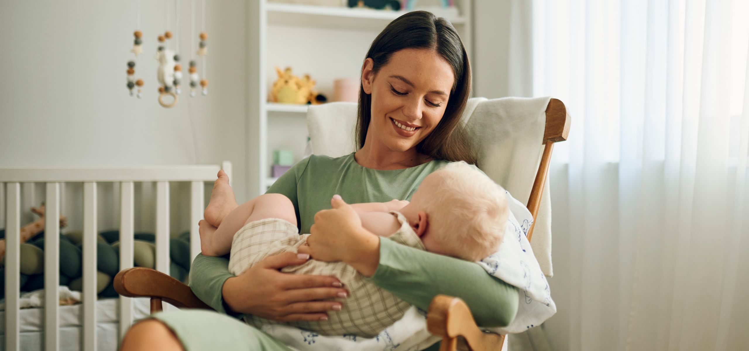 Majka drži bebu u naručju, spremna za dojenje nakon poroda.