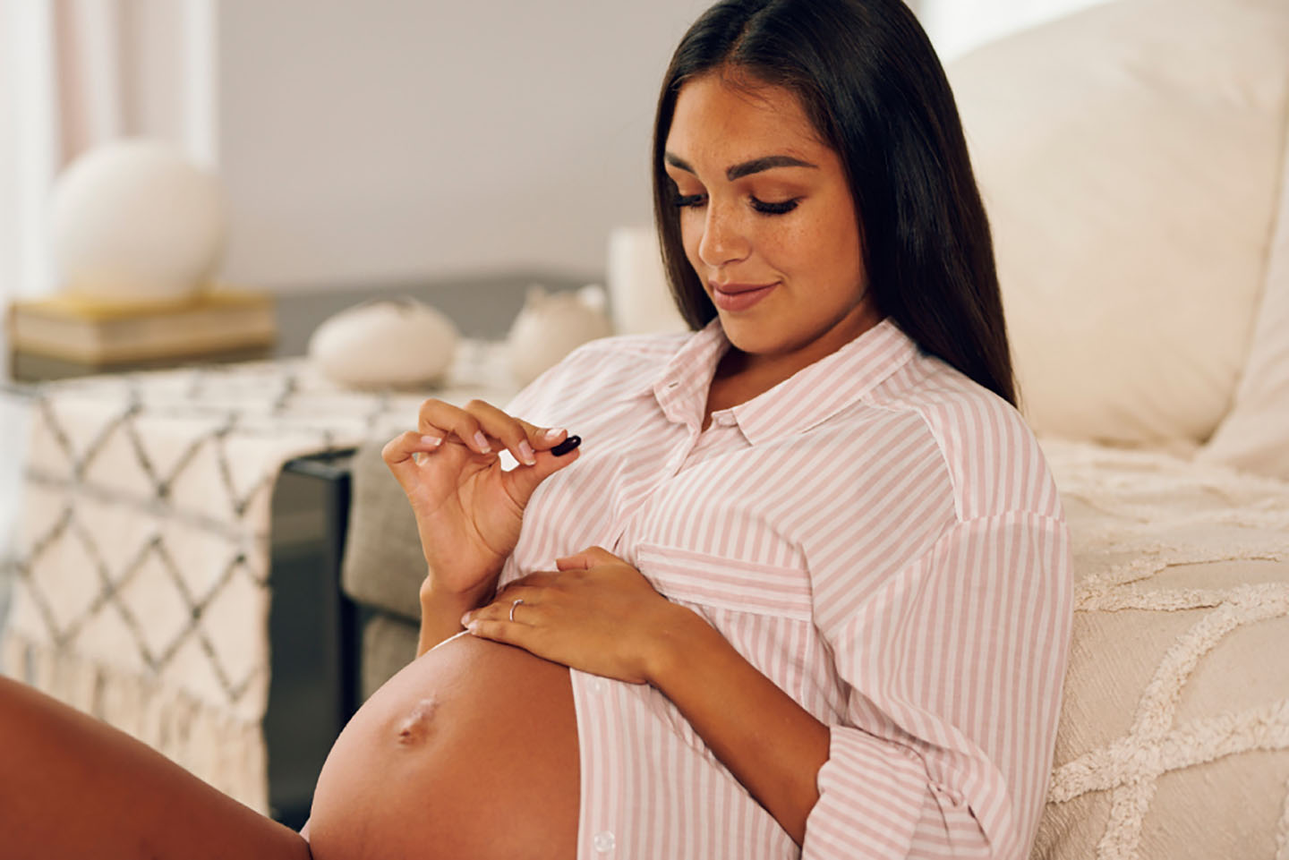 Trudnica u ružičastoj haljini drži Novalac Prenatal – dodatak prehrani za zdravlje tijekom trudnoće.