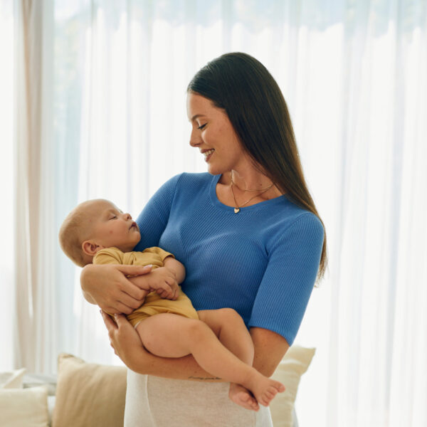 Majka drži novorođenče u svijetloj sobi – sretni trenuci ljubavi i njege.