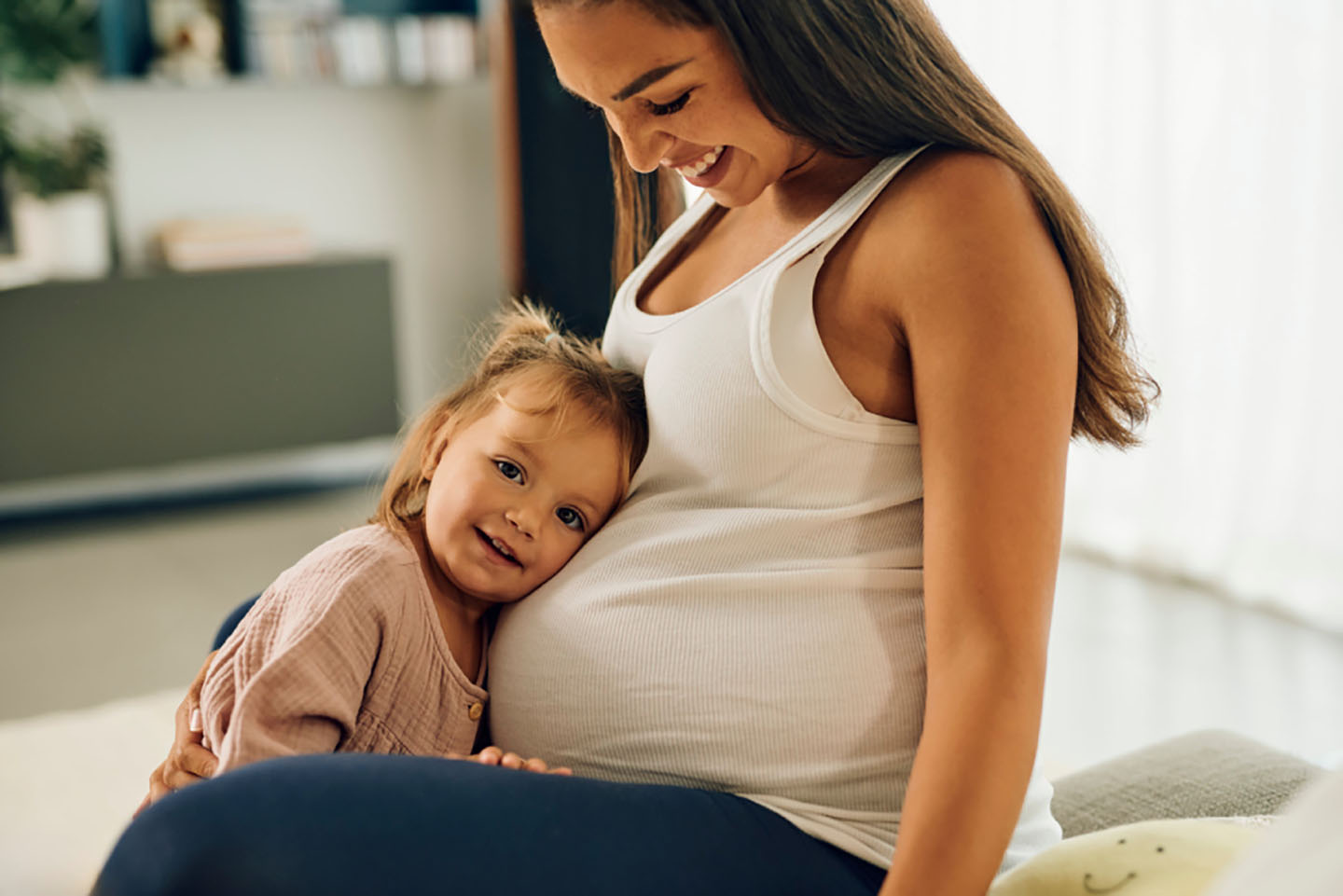 Djevojčica grli trbuh trudne majke – nježni trenuci očekivanja bebe.