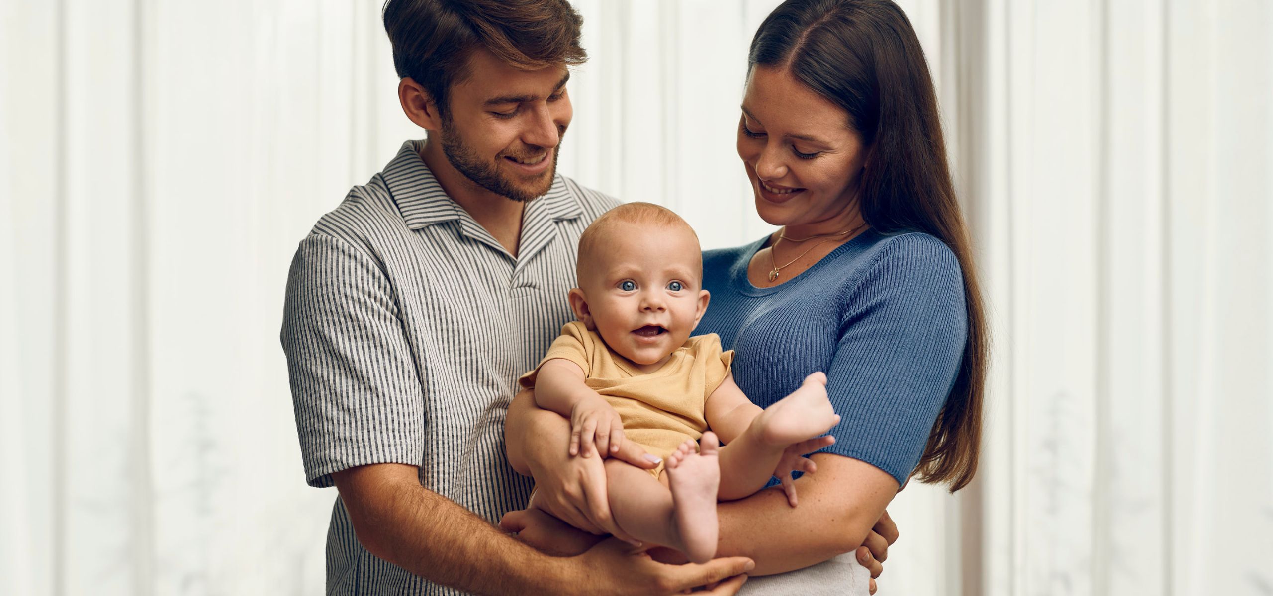 Majka i otac drže svoju bebu u naručju – sretna obitelj u zajedništvu.
